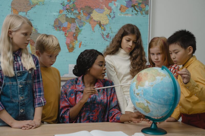 girl in white long sleeve shirt holding blue and white globe